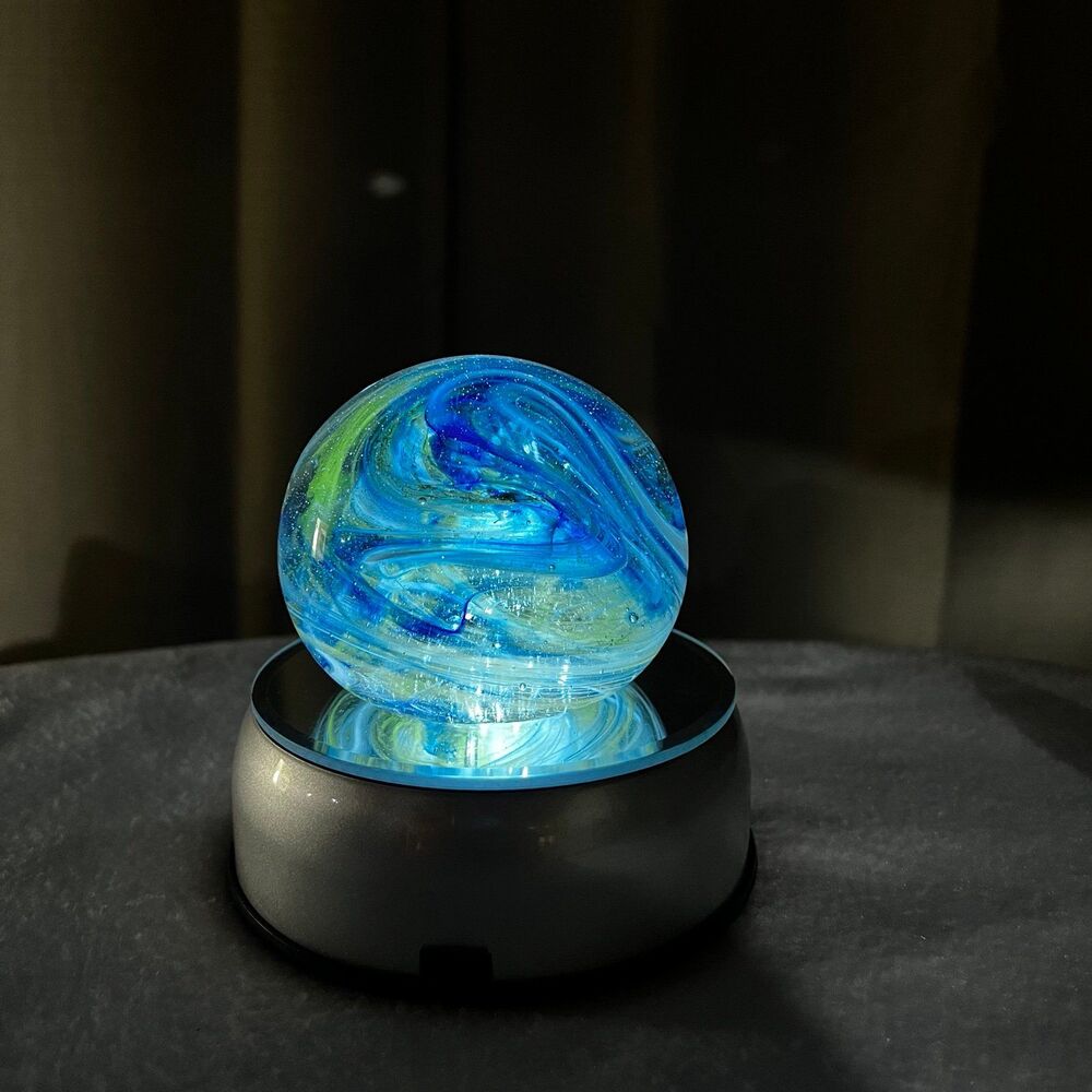 Clear glass round paperweight with blue and green swirls